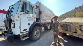 Sgt Kevin Duke of CO Nat'l Guard gives the go-ahead to a local trash truck on Upper Cattle Creek Rd.