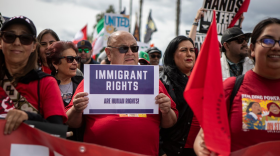A protester holds an immigrant rights sign while marching during the UFW march through Delano on March 31, 2025.