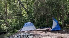 A tent on a dirt trail next to a creek