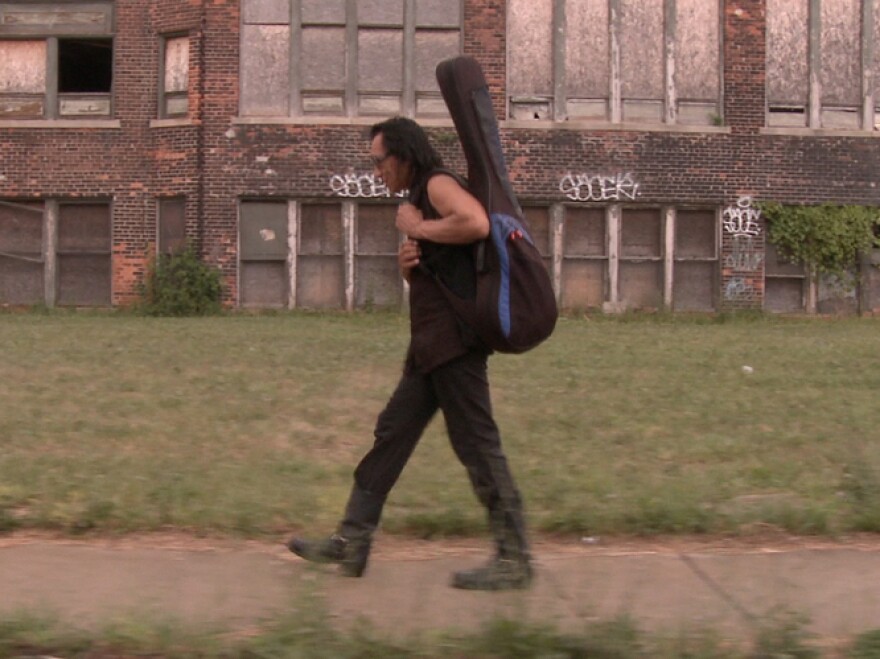 Rodriguez carries his guitar through Detroit, Mich., his hometown.