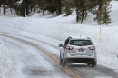 Car driving on Northeast Entrance Road lined with tall snowbanks.