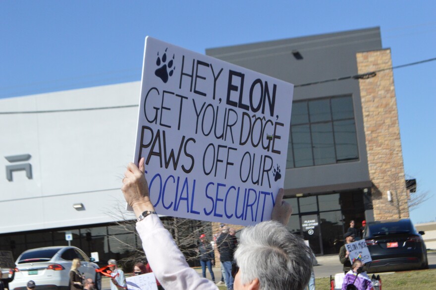 A protestor holds up a sign at a Tulsa Tesla store demonstration on Saturday, March 22, 2025.