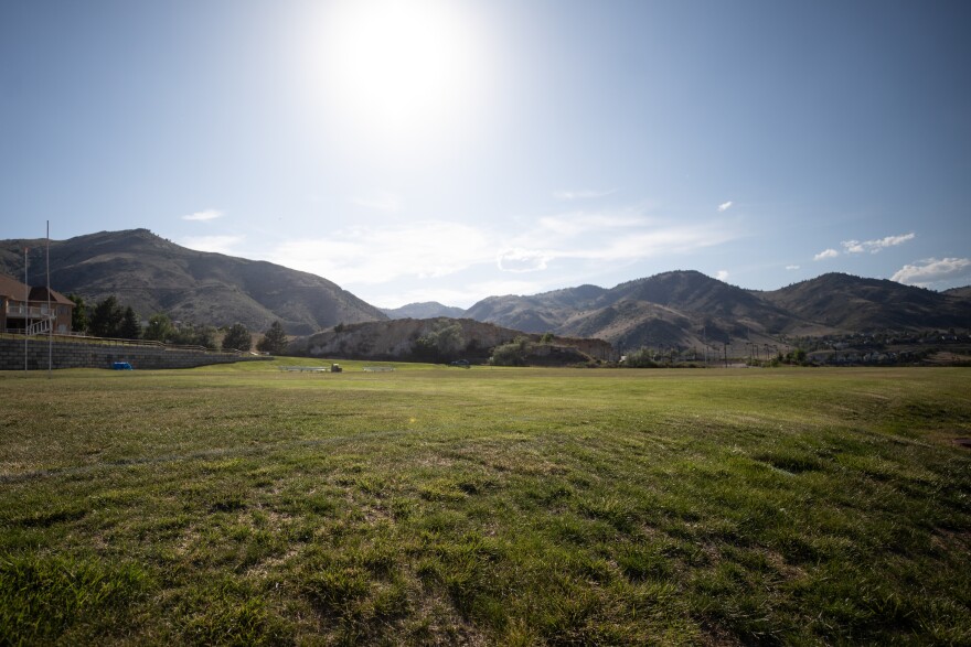The Colorado School of Mines campus with a large field in the foothills of the mountains.
