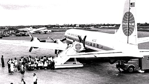 group in BW image gather to get on a Pan Am plane in the 1960s 