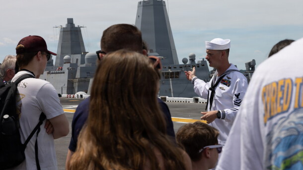 Navy Aviation Boatswain’s Mate 2nd Class Christian Prior leads a tour of USS Iwo Jima during a guided ship tour as part of SAIL250 in Norfolk, Virginia. Summer is the peak time for military families to change stations.
