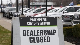 A close-up of a sandwich board with a sign that reads "preemptive covid-19 action - dealership closed"