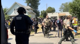  Law enforcement officers walking away from house.