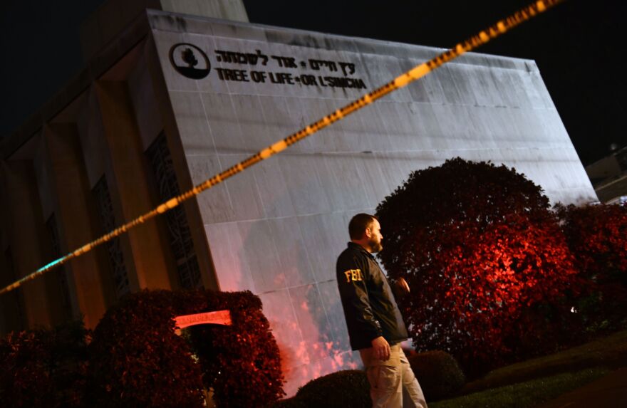 An FBI agent stands behind a police cordon outside the Tree of Life Synagogue after a shooting there left 11 people dead in the Squirrel Hill neighborhood.