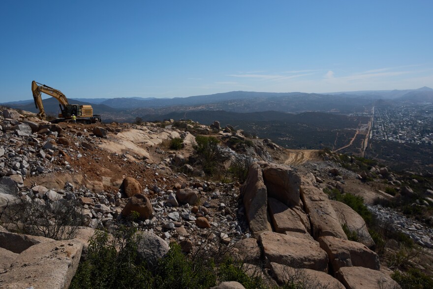 Construction crews work on a new border wall segment on Kuuchamaa Mountain, Friday, April 24, 2026, seen from Tecate, Mexico. (AP Photo/Gregory Bull)