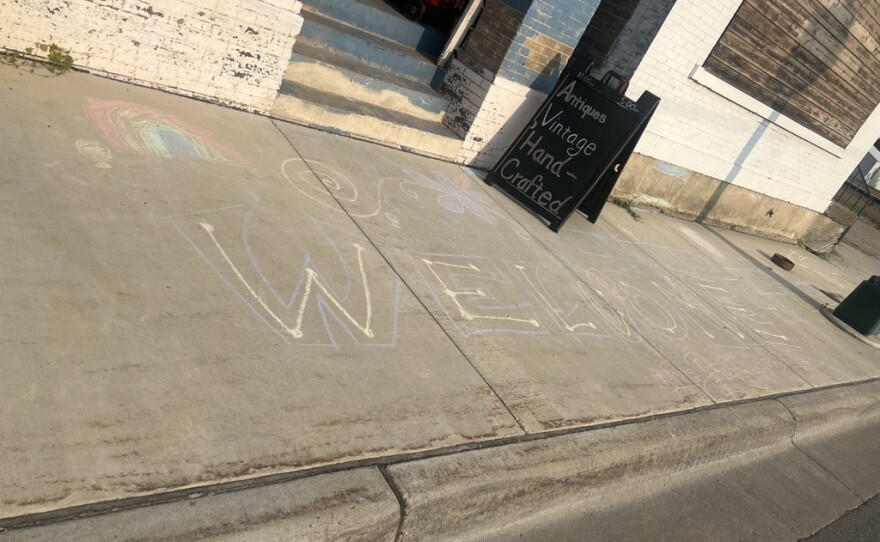 "Welcome" is written in sidewalk chalk in front of a store. 
