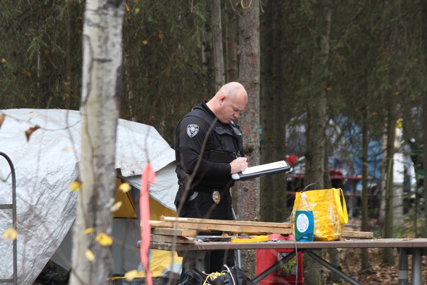 An Anchorage Police officer writes an eviction notice for a homeless camper at Centennial Campground. (