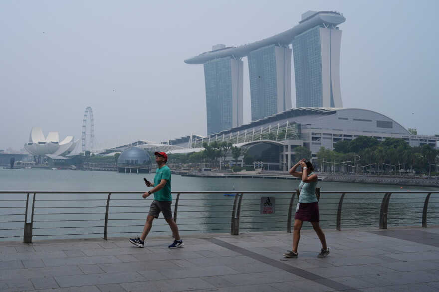 People exercise along the Marina Bay waterfront promenade as the Marina Bay Sands resort is shrouded in transboundary haze from fires in Indonesia, pushing the city’s air quality back into the unhealthy range, Monday, Sept. 14, 2026 in Singapore.
