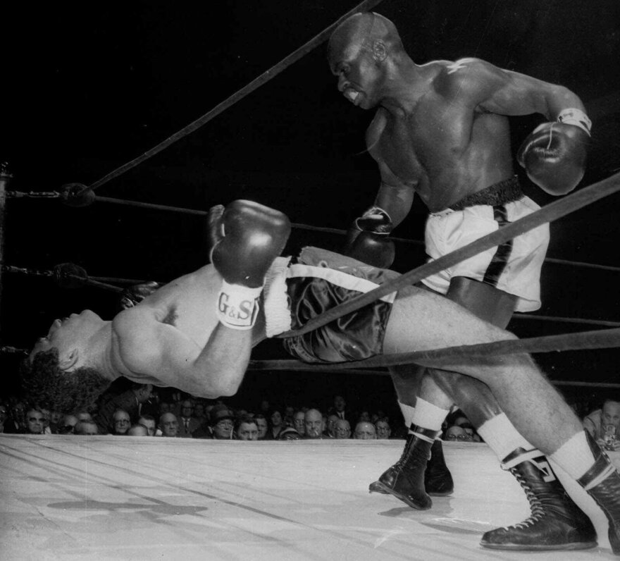 Rubin Carter of Paterson, N.J. watches Florentino Fernandez of Cuba fall through the ropes during their 1962 fight, after Fernandez was knocked out in the first round at New York's Madison square Garden. Carter has died at age 76.