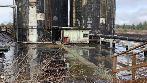 Two large, rusted towers on a waterlogged site. 