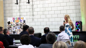 A woman stands in front of a crowd giving a speech