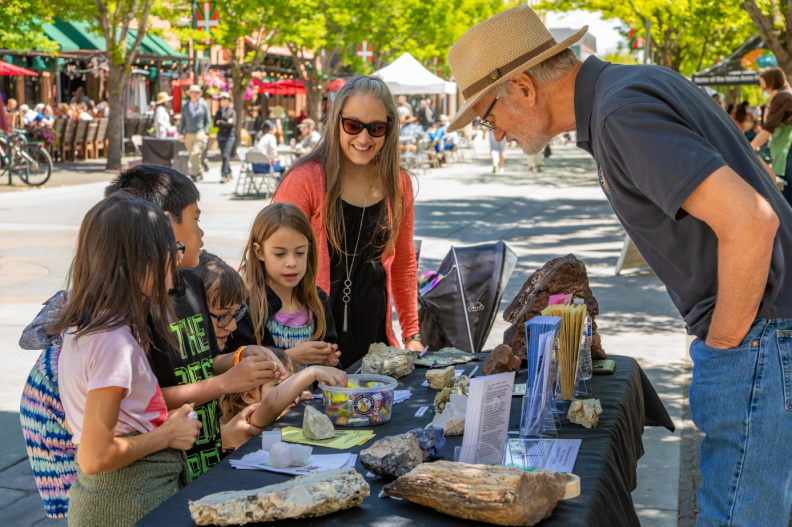A group of people standing around a table that has various times on it.