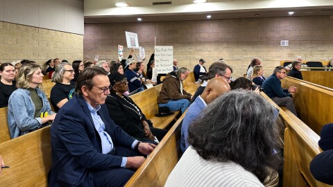 Utility Commissioner Donald van der Vaart interrupted the hearing to ask audience members to lower their anti–data center signs.