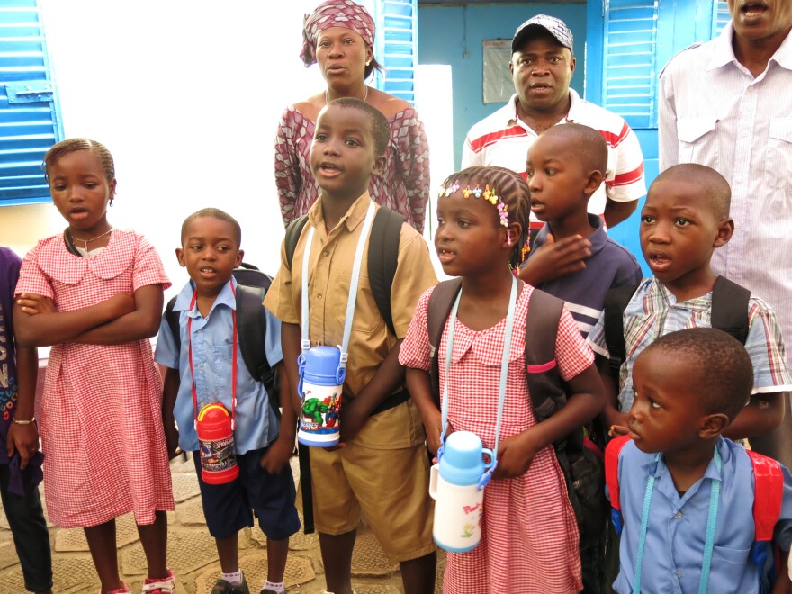 Children and teachers sing the national anthem on Monday morning, their first day in school since July.