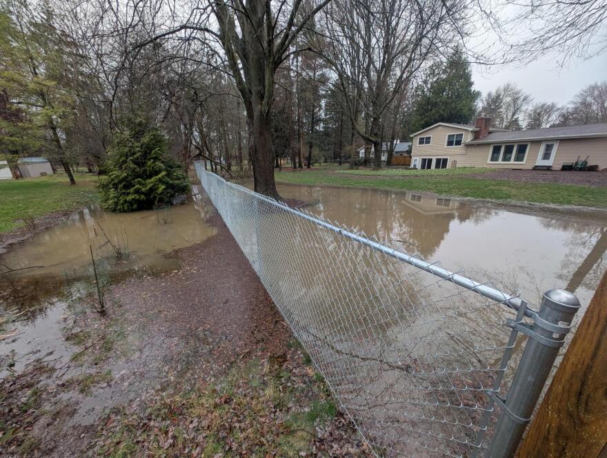 A flooded backyard with a fence in East Lansing