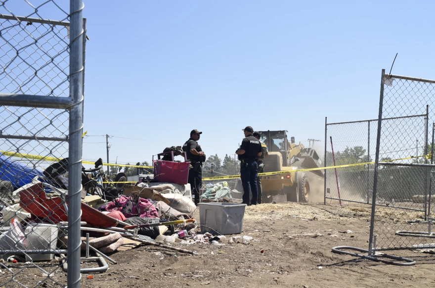 Law enforcement officers watch as heavy machinery clears the encampment on Eaton and Cohasset roads in Chico, Calif., on Aug. 5, 2024.