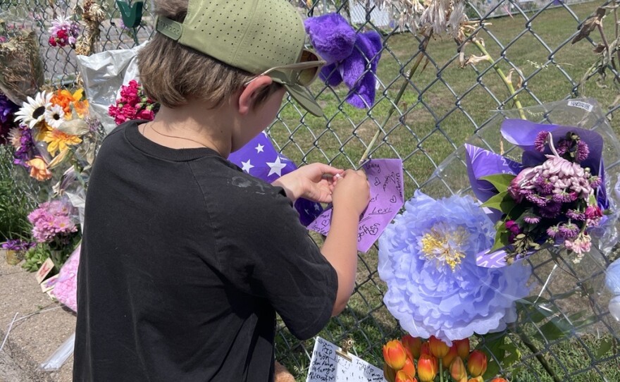 Landon Gorton attaches a purple paper heart to a chain-link fence outside the Brainerd home of Lexi Thornton on July 17, 2026. Thornton, 13, died by suicide on July 10. Gorton was once her neighbor and played with her.