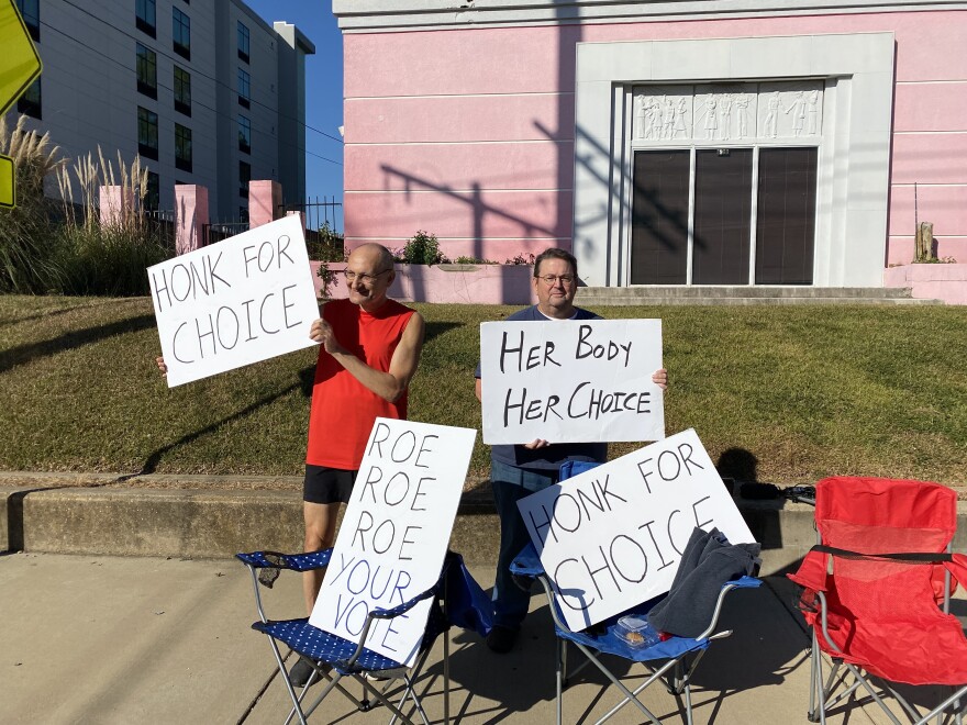 John Osborne (left) and Philip Harizi (right) stand outside the closed Jackson Women's Health Organization in Jackson, Mississippi. The two men are holding signs that read "Honk for choice," Her body her choice" and "Roe Roe Roe your vote."