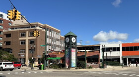 A green clocktower stands on a street corner