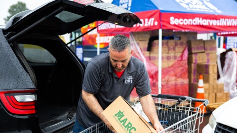 Daniel Weber, a truck driver at Second Harvest Food Bank of Northwest North Carolina, loads a box of produce into a vehicle during a food distribution. Photograph courtesy of Second Harvest Food Bank of Northwest North Carolina