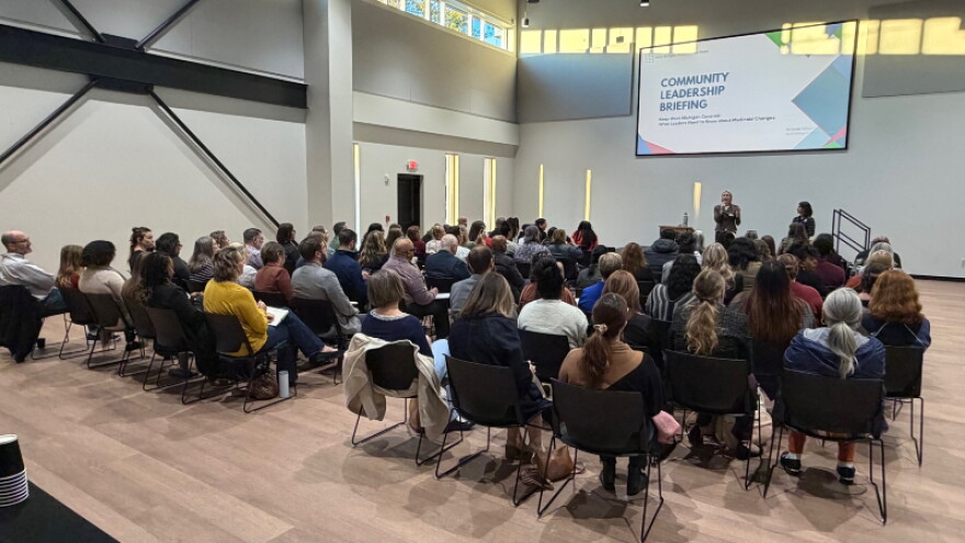 Megan Erskine (standing, center) and Dr. Nirali Bora (standing, right) speak to community and healthcare leaders at a West Michigan Medicaid Task Force briefing.