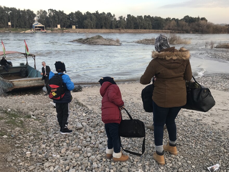 Mahmud, 11, Ayyub, 7, and their mother, Felicia Perkins-Ferreira, walk toward the boat that will take them out of Syria, across the river to Iraq, so they can start their journey home to Trinidad.