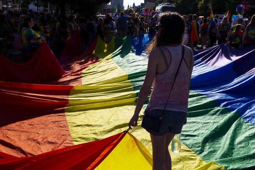 Parade participants hold a large Pride flag as they wait for the parade to begin.