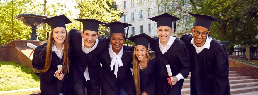 Group of happy diverse university students in caps and gowns