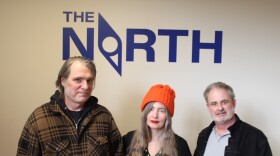 From left to right band members: Rich Matson, Germaine Gemberling, and Chris Petrack. Posing in from of a logo that reads "The North" in royal blue lettering. The letter O in north is in the shape of a compass. 
