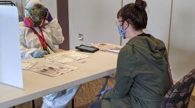 An election official in Kenosha, Wis., with a voter on April 7. Nearby Milwaukee says it's recorded at least seven coronavirus cases related to the state's controversial decision to move forward with in-person voting.