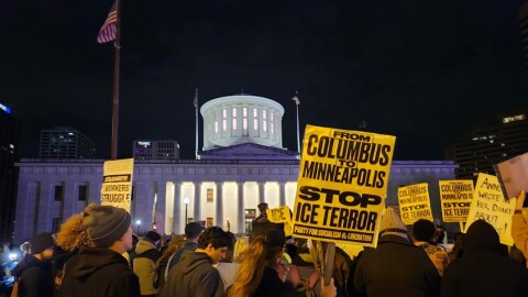 Protesters gather at night at the Ohio Statehouse. They hold signs, including one that reads, 'From Columbus to Minneapolis stop ICE terror / party for socialism and liberation. 