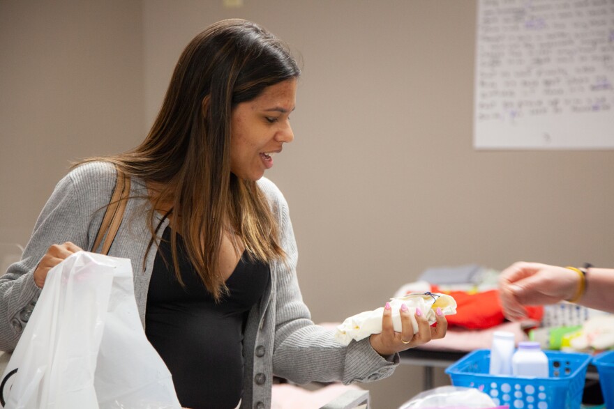 Talita Sonsini, from Brazil, picks bibs for her daughter at a community baby shower in Nashua, April 12, 2023.