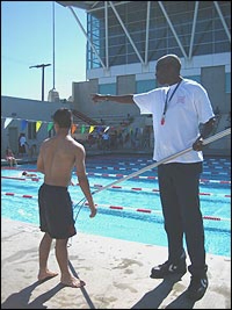 Andre Brent, manager of the Argue pools, helps assess the progress of young swimmers. His shepherd's crook is at hand if a swimmer tires and needs to be pulled to the pool's edge.