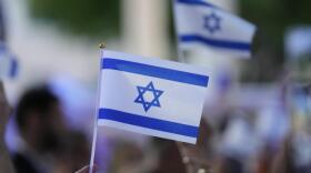 People wave Israeli flags during an empty Shabbat table event honoring those kidnapped by Hamas in Israel, Thursday, Nov. 2, 2023, at Temple Beth Sholom in Miami Beach, Florida. (Wilfredo Lee/AP)