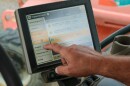 A man points to a screen inside a tractor. Sugar beet and dry edible bean farmer Clint Stoutenburg of Sandusky, Michigan points out all of the different settings and diagnostics that are available in the bed of his John Deere tractor.   