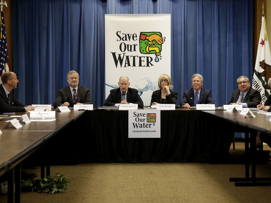 California Gov. Jerry Brown, middle, talks to reporters after a three-hour meeting on the drought with agricultural, environmental and urban water agency leaders from across California. Brown introduced statewide water cutbacks earlier this year.