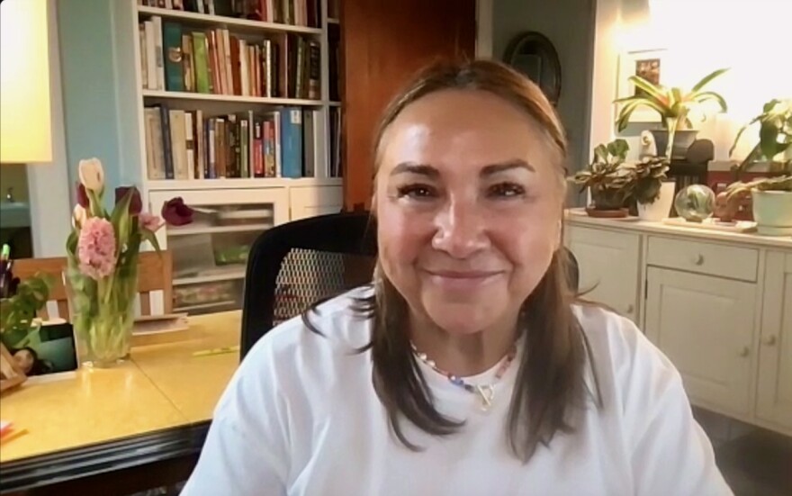 A woman in a home office smiles for a Zoom screen shot