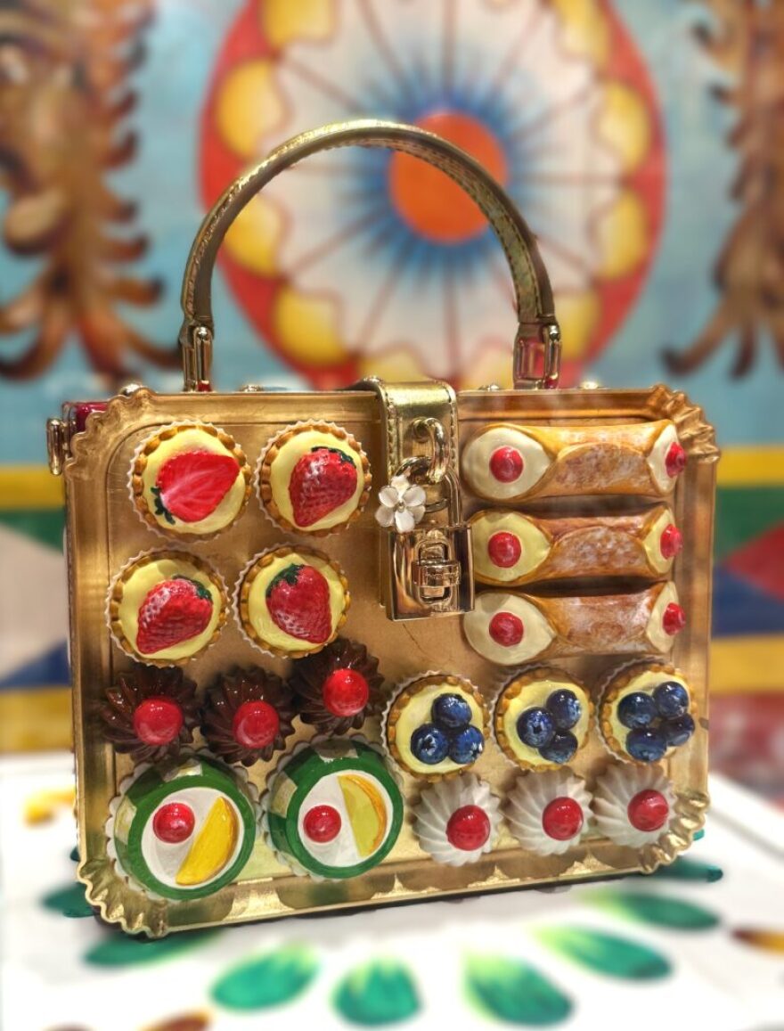 In the display dedicated to Sicily, a whimsical purse is decorated with jeweled cannoli and other regional sweets in “From the Heart to the Hands: Dolce&Gabbana.”