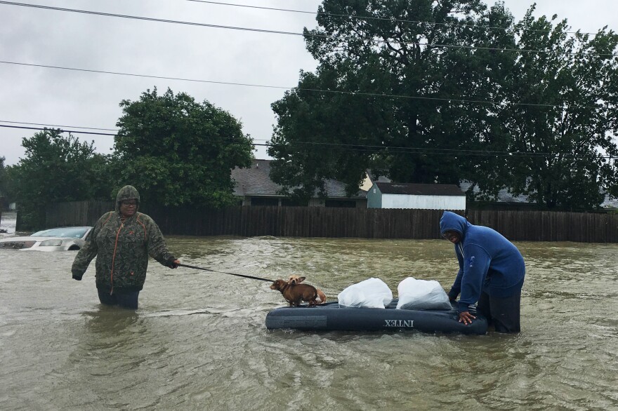 Amber and Curtis Fletcher evacuate their neighborhood with their dogs in northeast Houston, using an inflatable twin mattress they had at their house.