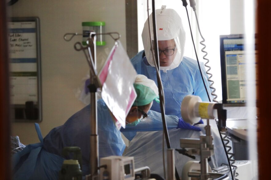 FILE - In this May 8, 2020, file photo registered nurses Beth Andrews, top, and Erin Beauchemin work with a patient in the COVID-19 Intensive Care Unit at Harborview Medical Center in Seattle. (AP Photo/Elaine Thompson, File)