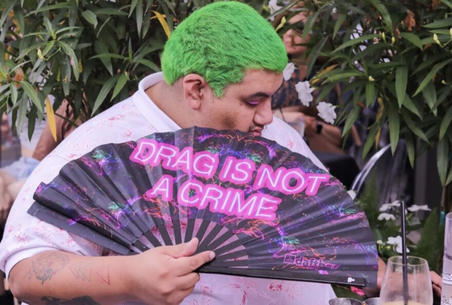 Attendee at ReBar’s drag brunch accessorizes with a neon fan that says “DRAG IS NOT A CRIME”