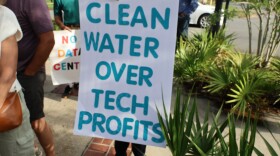 Protestor holds up a sign that reads "Clean Water Over Tech Profits"