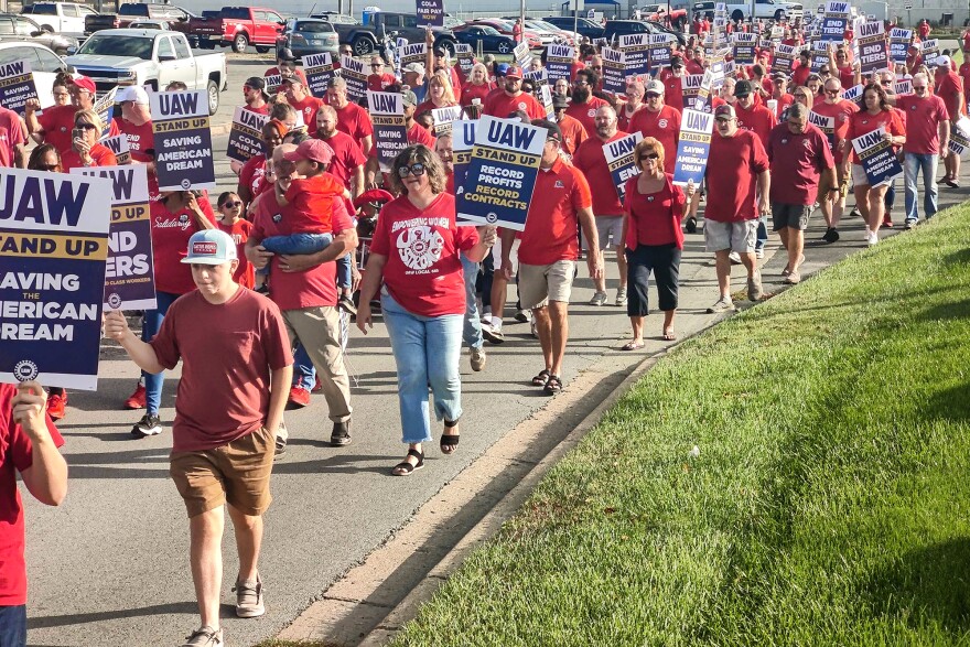 People dressed in red and carrying UAW signs march during a strike.