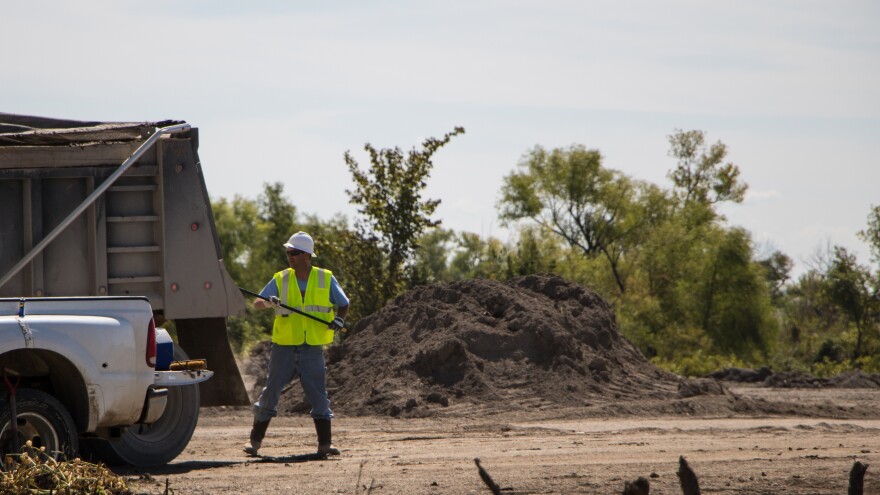 A worker brushes dusty mine waste off a truck before it exits the contaminated site.