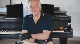 Brazilian pianist Joao Carlos Martins poses for pictures wearing bionic gloves at his home in Sao Paulo, Brazil, Wednesday, Jan. 22, 2020. (AP Photo/Andre Penner)
