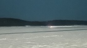 The headlight of race judge Steven Hilton's borrowed snow machine seen from the banks of the Yukon River on Feb. 14, 2026. Hilton was stuck for about an hour. (Shelby Herbert/KUAC)